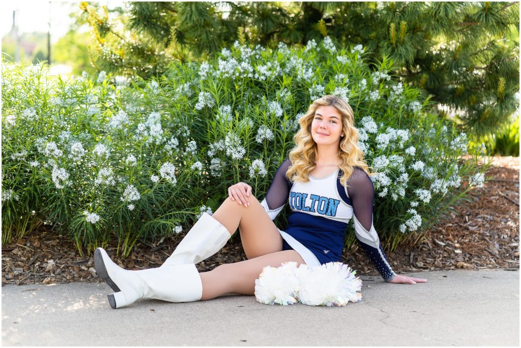 senior girl poses in dance uniform in front of a flowered bush for her senior portrait session in Columbia, Missouri with West Plains Missouri Wedding and Senior Portrait photographer, Hannah Carr Photography.