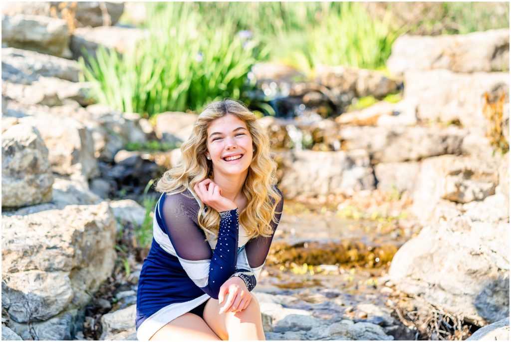 senior girl poses near a waterfall in her dance uniform at Stephens Lake Park in Columbia Missouri for her senior portrait session with West Plains Missouri Wedding and Senior Portrait photographer, Hannah Carr Photography.