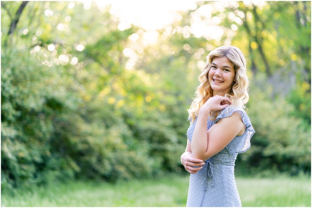 senior girl poses in a grassy field at Grindstone Nature Area in Columbia Missouri at sunset for her senior portrait session with West Plains Missouri Wedding and Senior Portrait photographer, Hannah Carr Photography.