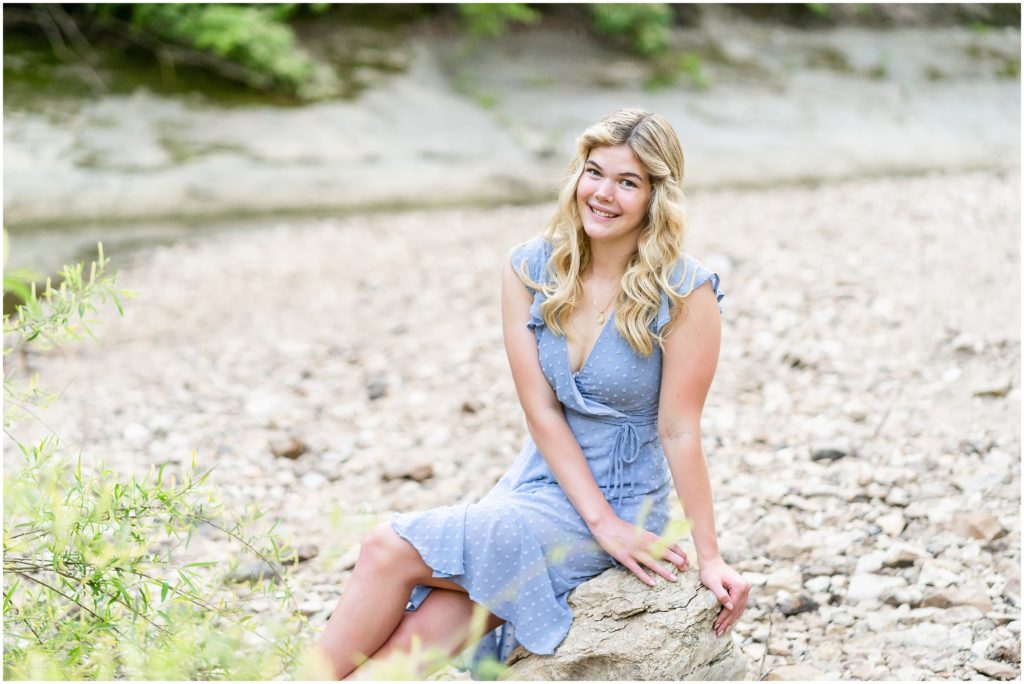  senior girl poses on a rock near a creek at Grindstone Nature Area in Columbia Missouri at sunset for her senior portrait session with West Plains Missouri Wedding and Senior Portrait photographer, Hannah Carr Photography.