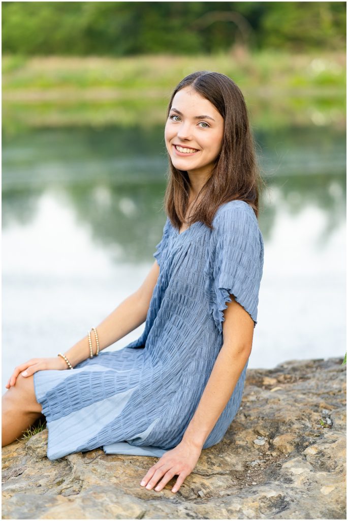 Senior girl poses on a rock by a pond at Nifong Park in Columbia, MO for her senior portrait session with West Plains, MO photographer, Hannah Carr Photography