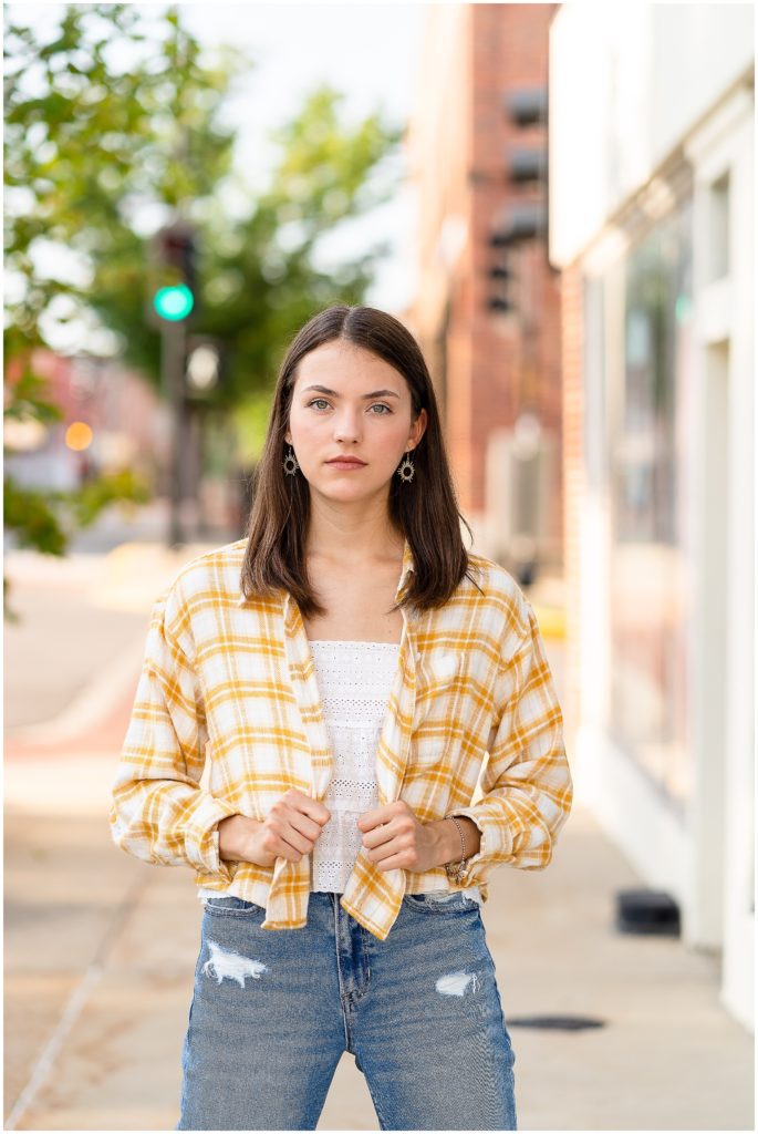 Senior girl poses on a sidewalk in downtown Columbia, MO for her senior portrait session with West Plains, MO photographer, Hannah Carr Photography