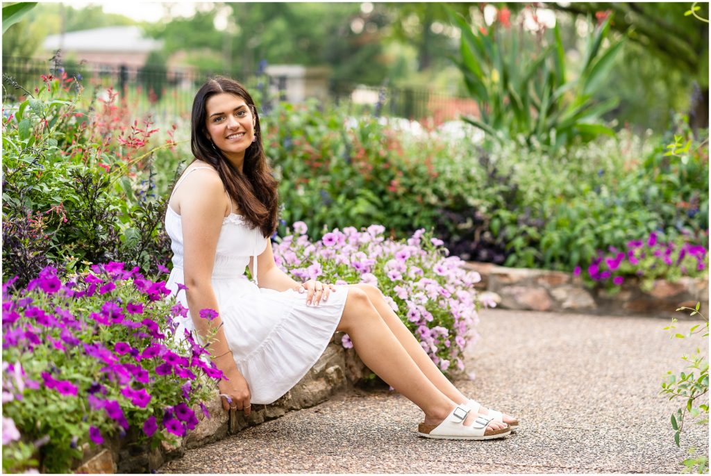 Senior girl poses by a flower bed at Shelter Gardens in Columbia Missouri for her senior session with West Plains Photographer, Hannah Carr Photography.