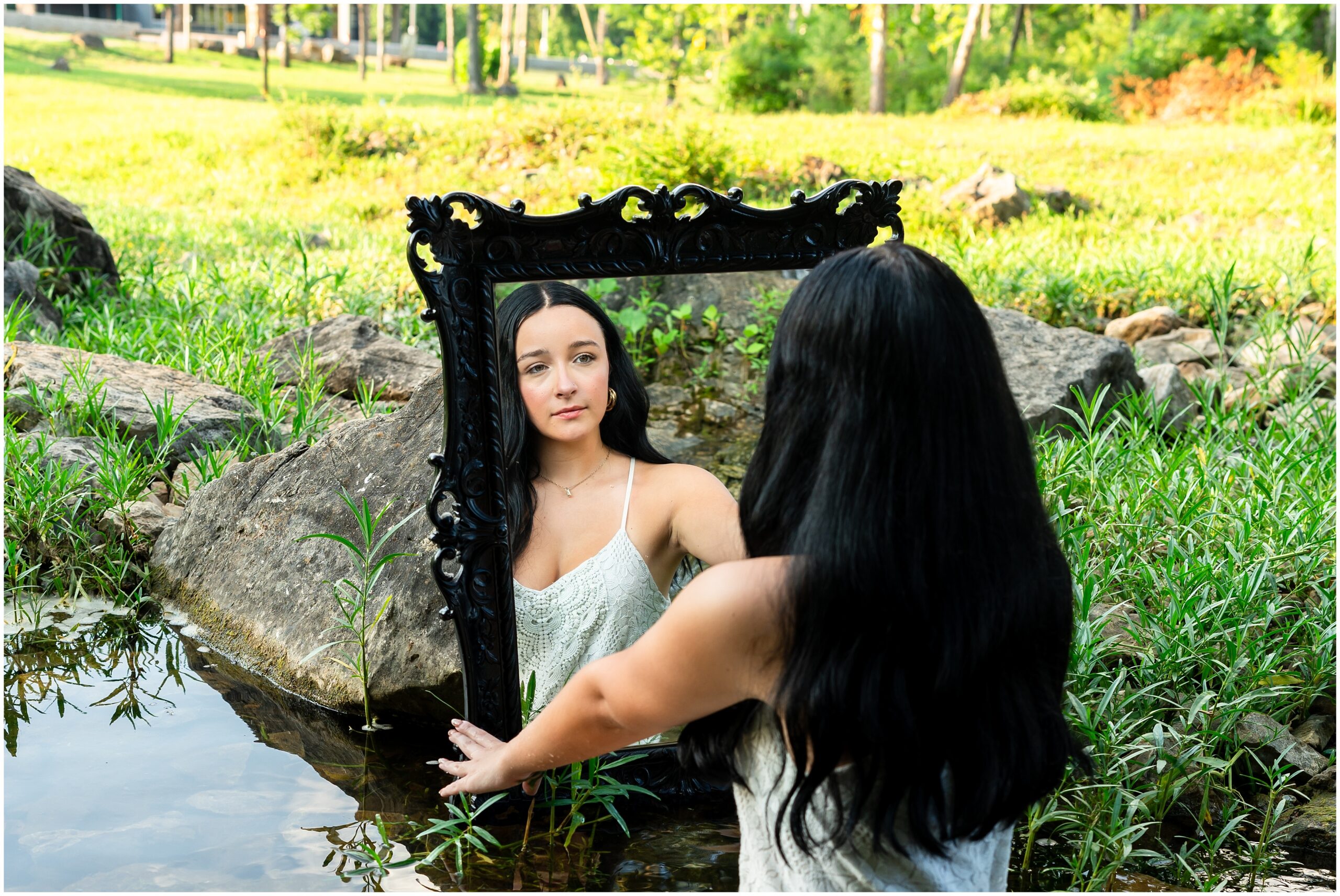 Highland High School senior, Dacy-Lynn, poses with a mirror in a stream in beautiful Cherokee Village, AR for her senior session with North Arkansas Senior Photographer, Hannah Carr Photography.